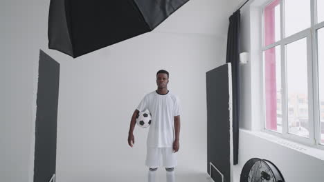 Art-director-checking-the-photos-on-a-monitor.-Professional-crew-team-together-in-the-studio.-Behind-the-scene-of-photo-shooting-Professional-football-player-and-production-set-up-in-the-big-studio.